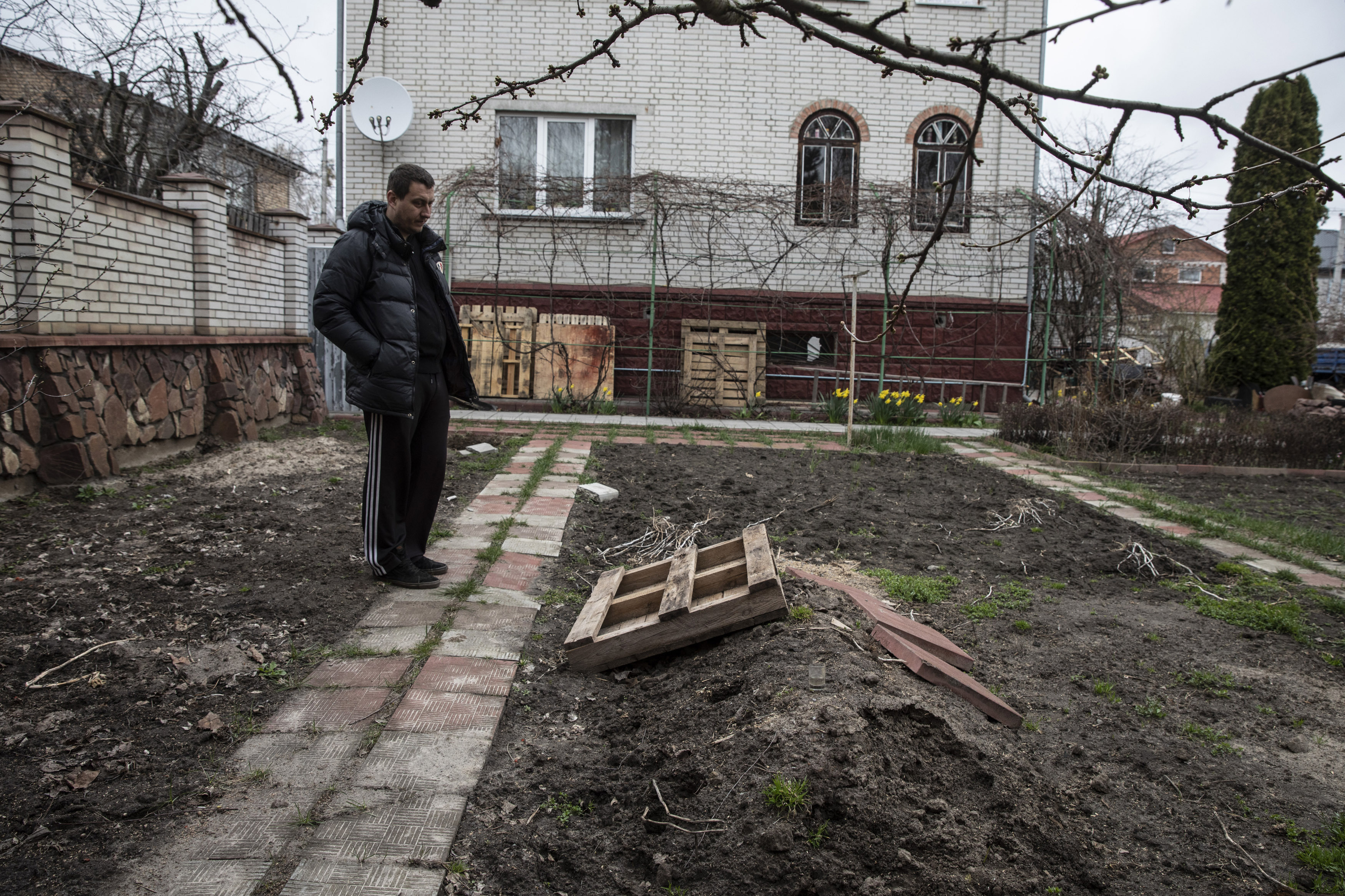 Pavlo Prykhodko stands by his father's grave in the backyard of his parent's home in Vorzel, Ukraine, on April 13. MUST CREDIT: Photo for The Washington Post by Heidi Levine.